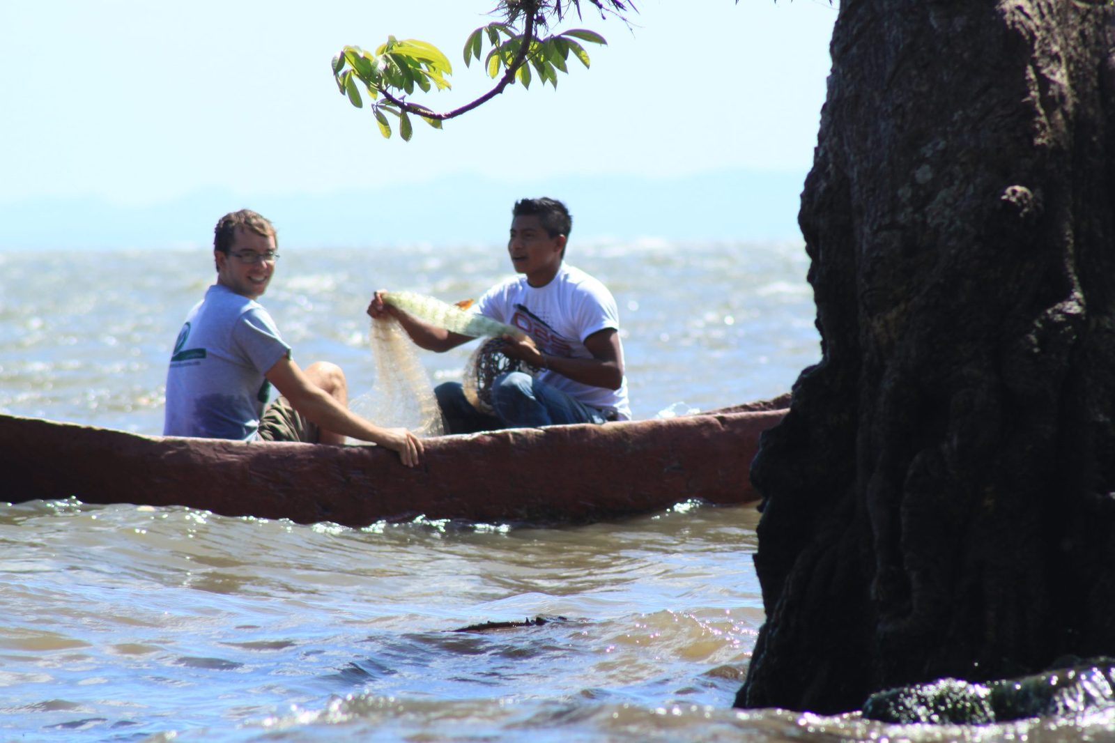 A visitor and local guide fishing together from a dugout canoe on the shimmering waters of Lake Nicaragua