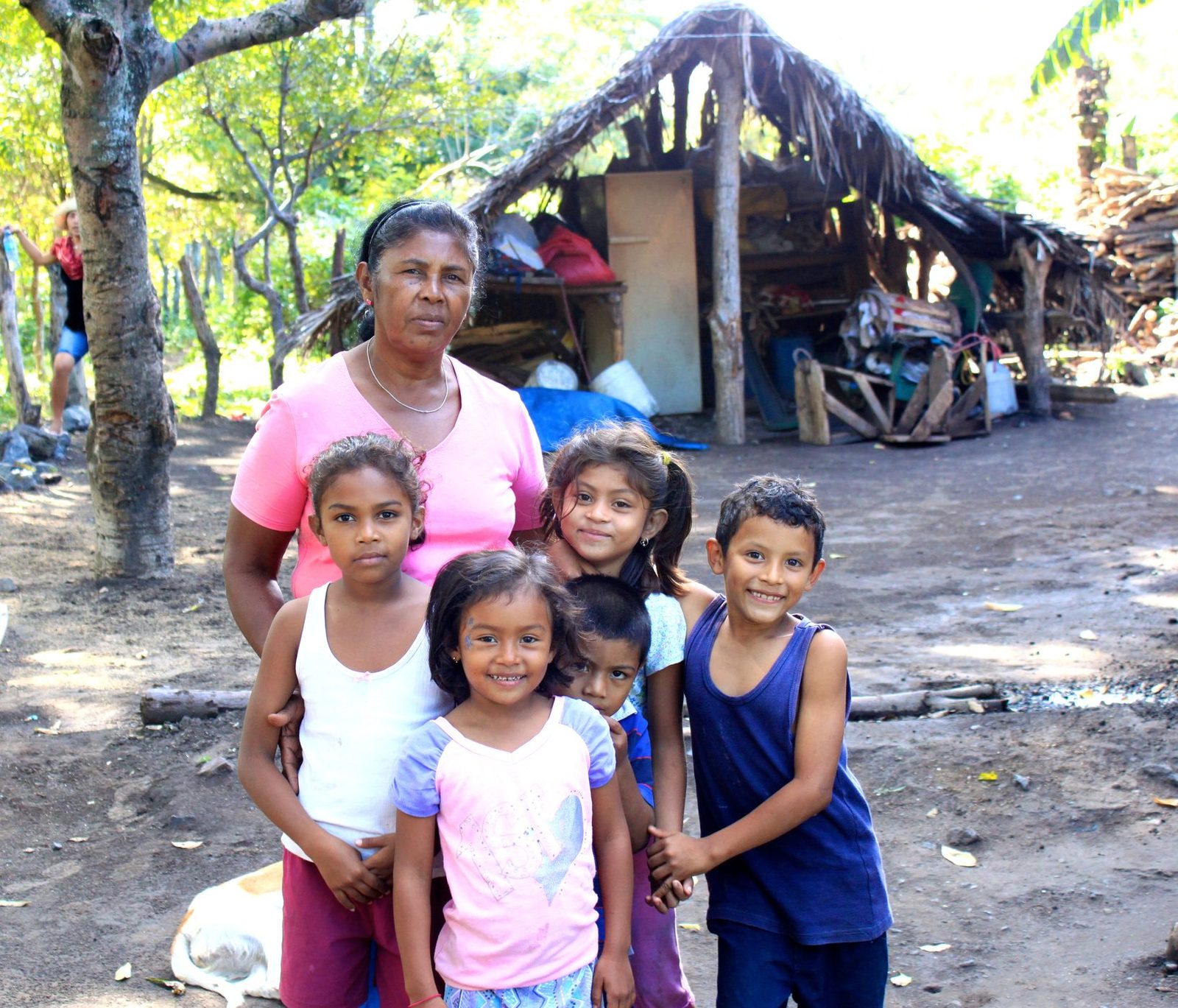 A grandmother from Los Ramos standing with four smiling children in front of their family homestead