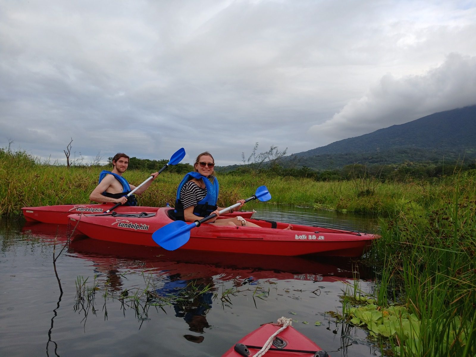 Two kayakers paddling on the Istian River with Ometepe's volcano in the background