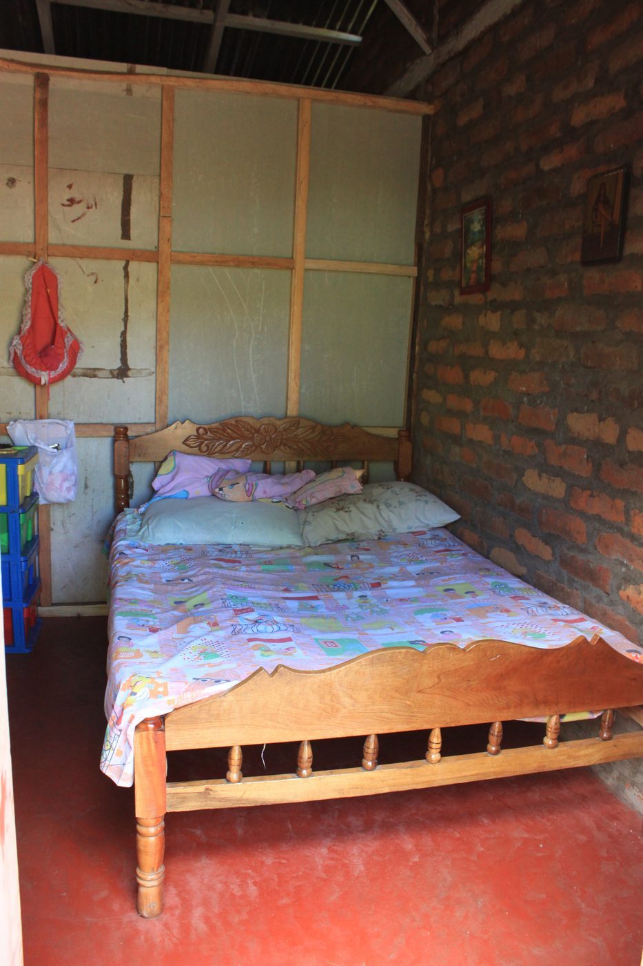 A cozy bedroom inside a Los Ramos homestay with a carved wooden bed frame