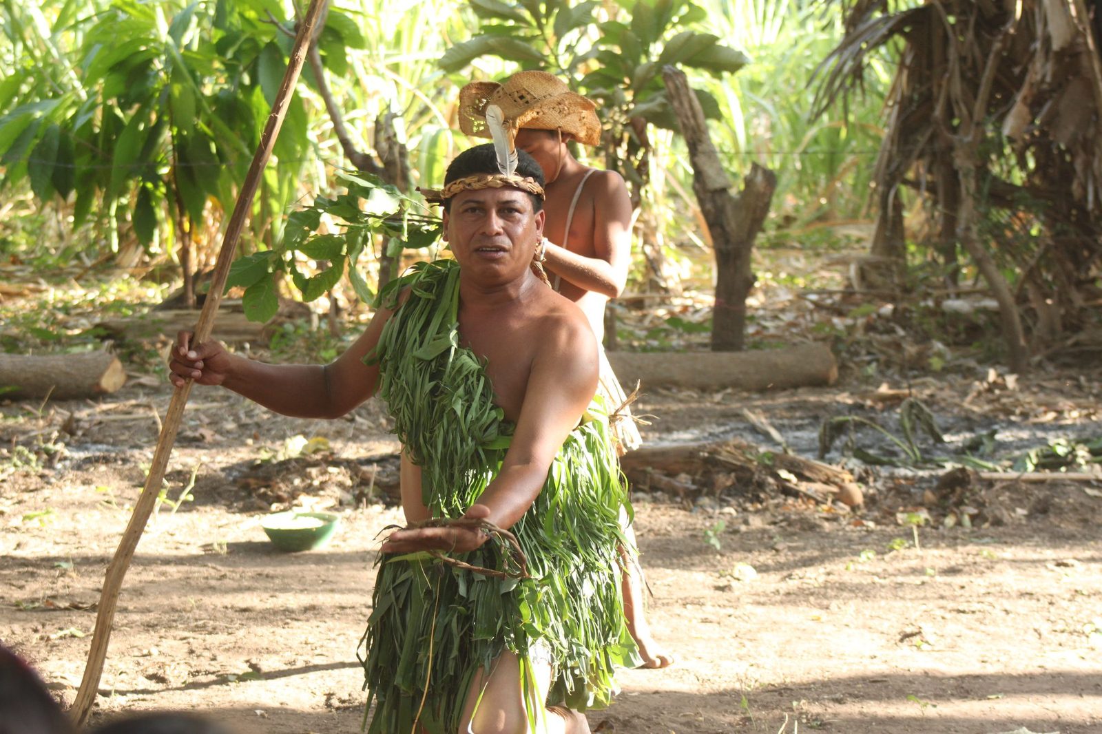 A male performer in traditional leaf costume holding a spear during a cultural storytelling performance